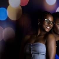 Two grads smile and pose at photo booth backdrop